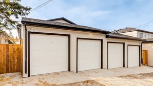 Un garaje con cuatro puertas, numeradas del 3 al 6, y una cerca de madera a la izquierda.