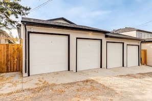 Un garage avec quatre portes, numérotées de 3 à 6, et une clôture en bois sur le côté gauche.