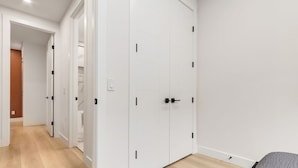 A room with a bed, a white wardrobe, and a wooden floor.