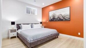A bedroom with a bed, nightstands, a window, and a wall-mounted painting. - Brand New Perfect Family Home, w/ Garage Parking (Calgary)