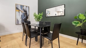 A dining area with a black table and chairs, a potted plant, and a wall-mounted mirror.