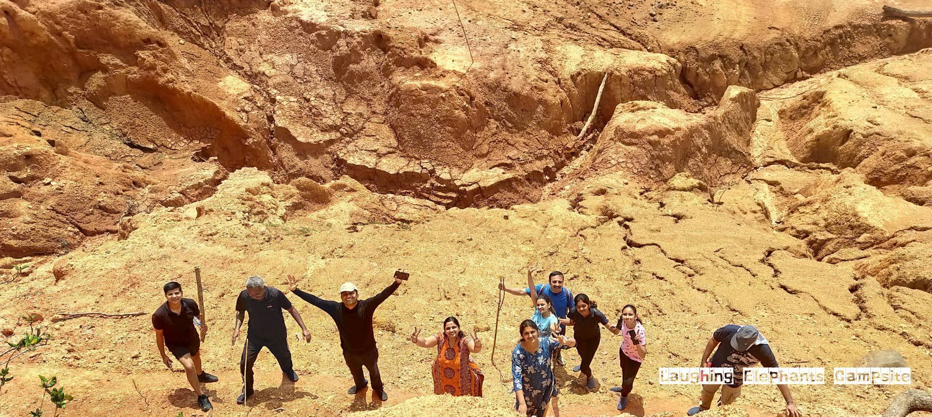 Un groupe de personnes se tient sur un terrain rocheux, sous un ciel dégagé.