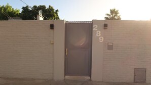 A gated entrance with a metal door, a brick wall, and the number 289 visible on the wall. - Gugasuites (Ezeiza)