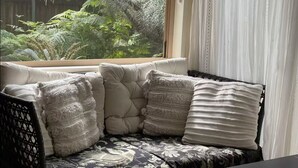 Ein Ecksofa mit Blick auf einen Garten durch ein Fenster.