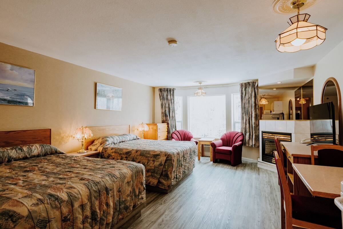A hotel room with two beds, a dining area, and a fireplace.
