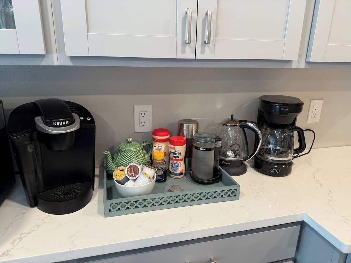 Eine Küchenarbeitsplatte mit Kaffeemaschine, Wasserkocher und verschiedenen Küchenutensilien.