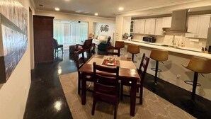 A modern kitchen with white cabinets, a microwave, and a bar area with stools. - Hot Tub | 2BR Duplex | Pet Friendly| Near Airport (San Antonio)