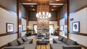 A spacious lobby with a central seating area, a fireplace, and framed artwork on the walls.