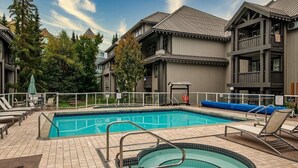 A swimming pool with a hot tub, lounge chairs, and a covered area with a lifebuoy.