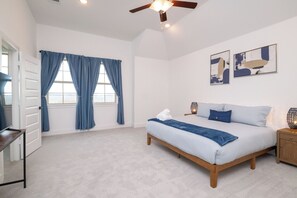 A bedroom with a bed, two windows with blue curtains, a ceiling fan, and two abstract paintings on the wall. - Lakefront, Boating + Private Deck - Marina Views (Rowlett)