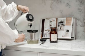 A person pouring water into a glass container on a kitchen counter. - Rubus Residences, Berry - by Linnaeus Collection (Berry)