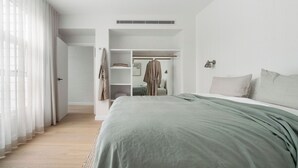 Een moderne slaapkamer met een groot bed, een inloopkast en uitzicht op de omgeving.