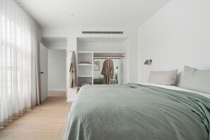 A modern bedroom with a large bed, a walk-in closet, and a view of the outdoors. - Rubus Residences, Berry - by Linnaeus Collection (Berry)