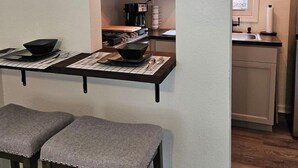 Une cuisine compacte équipée d’un four à micro-ondes, d’une machine à café et d’une petite fenêtre.