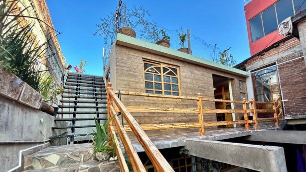 A building with a wooden staircase, a window with a wooden frame, and a stone wall. - SiempreViva Hospedaje By GEstores (Chignahuapan)