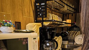 A kitchen counter with a microwave, coffee maker, and a person slicing an apple. - SiempreViva Hospedaje By GEstores (Chignahuapan)
