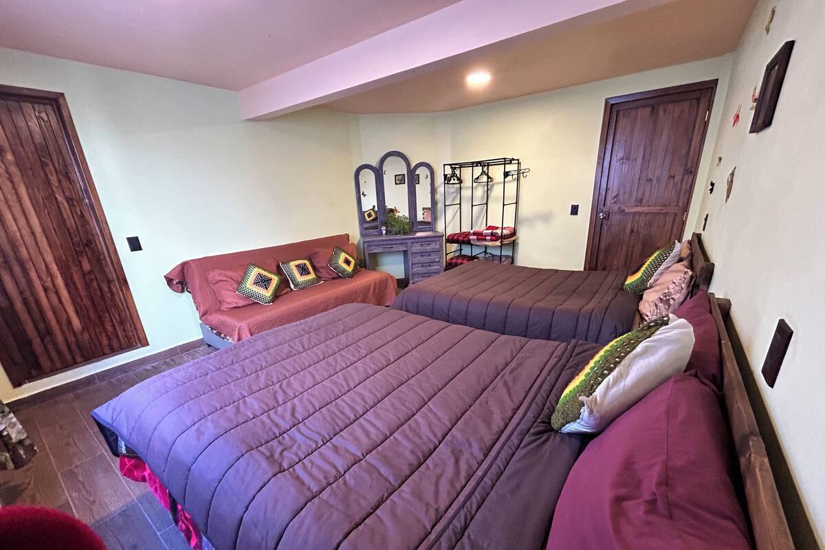 Un dormitorio con dos camas, un armario de madera, un espejo y un perchero.