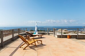 A rooftop terrace with two wooden lounge chairs and a flagpole, overlooking a coastal cityscape. - House with terrace in the heart of Naples: view of Vesuvius, Capri and Posillipo (Napoli)