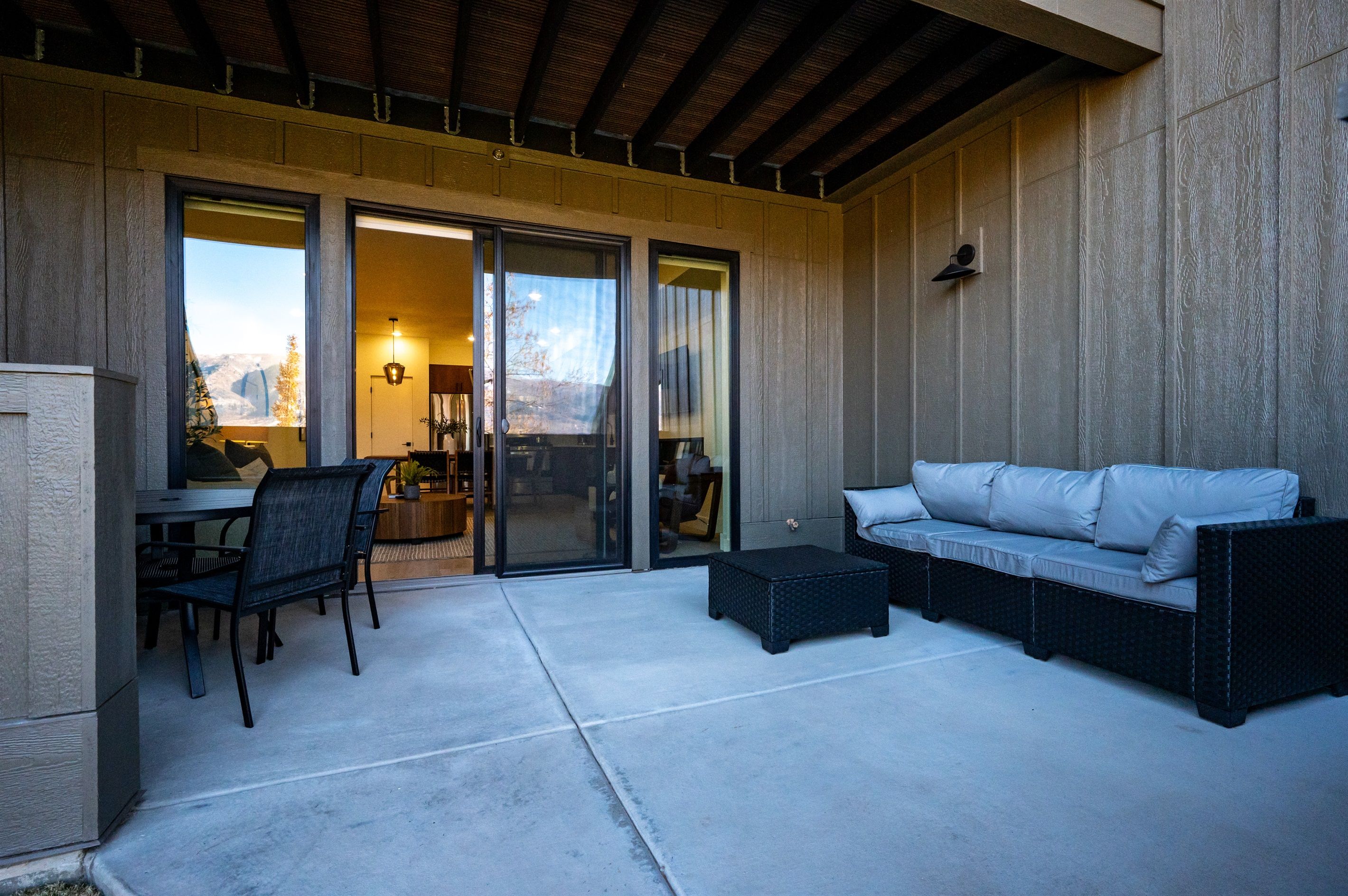 An outdoor patio area with a dining table and chairs, a sofa, and a small table.