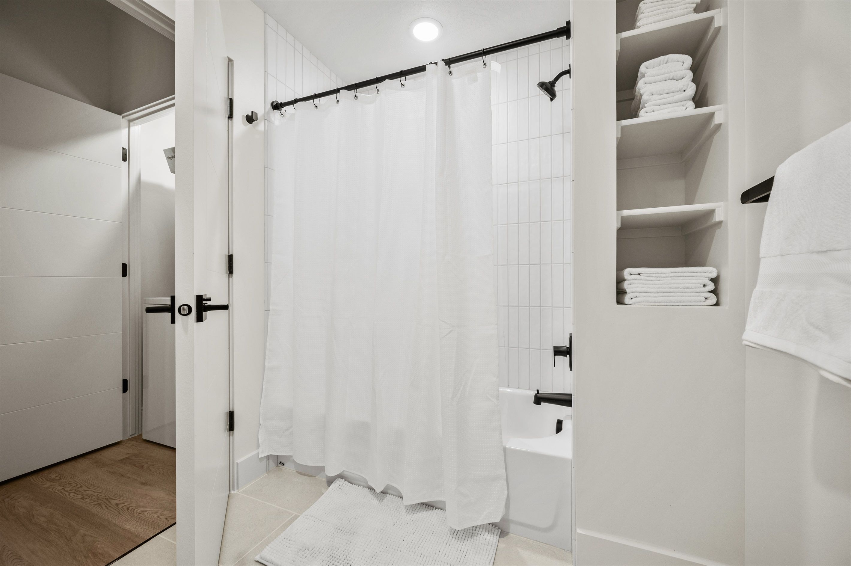 Un baño moderno con cortina de ducha, bañera y toallero con toallas dobladas.