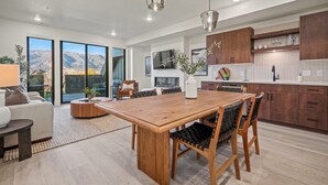 Une cuisine moderne avec des meubles en bois, une grande table à manger et des luminaires suspendus.