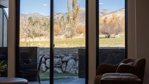 Une pièce dotée d’une grande porte-fenêtre coulissante donnant sur un patio avec un mur en pierre et une vue sur un paysage montagneux.