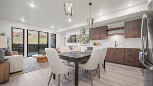 Une cuisine moderne avec un coin repas, des meubles en bois et un grand réfrigérateur.
