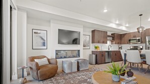Un salon moderne avec un canapé en cuir marron, une table basse et un téléviseur fixé au mur.