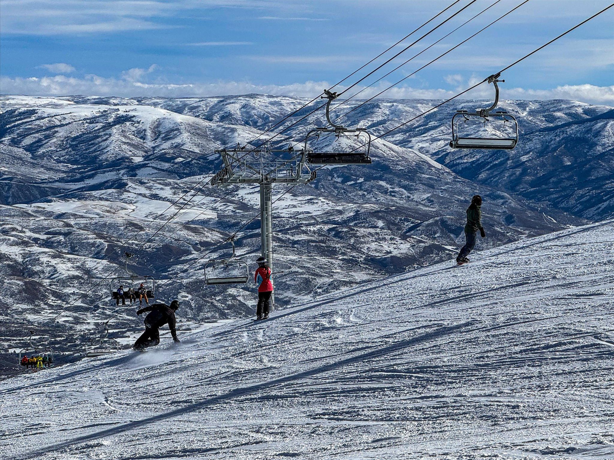A ski lift with skiers descending a snowy mountain slope.