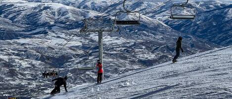 A ski lift with skiers descending a snowy mountain slope.