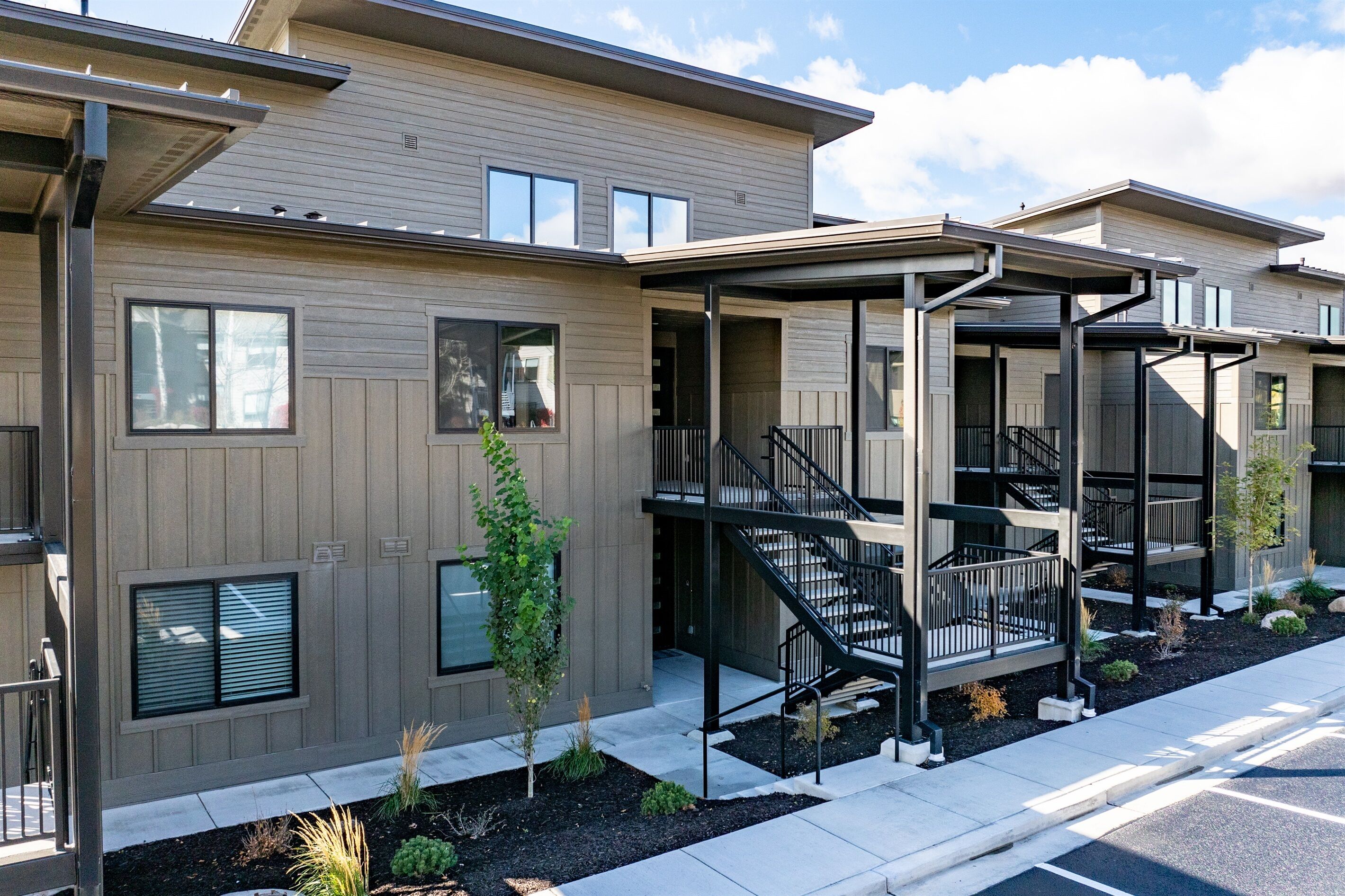 A modern multi-story residential building with balconies and a covered outdoor area.