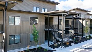 A modern multi-story residential building with balconies and a covered outdoor area.