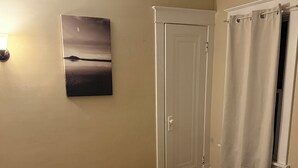 Une chambre à coucher avec un lit, une porte, une fenêtre avec des rideaux et un tableau accroché au mur.