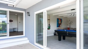 Un espace piscine intérieur moderne, doté d’une table de billard, d’un porte-queue et d’une peinture abstraite aux couleurs vives accrochée au mur.