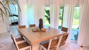 A dining area with a wooden table, white chairs, and a patterned rug. - Spacious 4-bedroom house in charming Port Charlotte with AC, WiFi, near beaches (Port Charlotte)