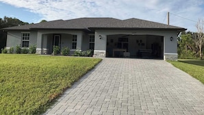 A single-story house with a garage, a paved driveway, and a well-maintained lawn. - Spacious 4-bedroom house in charming Port Charlotte with AC, WiFi, near beaches (Port Charlotte)