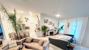 A modern living room with a sofa, coffee table, and a dining area with chairs and a table. - Spacious 4-bedroom house in charming Port Charlotte with AC, WiFi, near beaches (Port Charlotte)