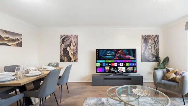 A modern living room with a dining area, a flat-screen TV, and artwork on the walls. - Barnet Oasis near Sky Studios (New Barnet)