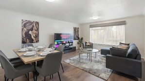 A modern living room with a dining area, a flat-screen TV, and a sofa. - Barnet Oasis near Sky Studios (New Barnet)