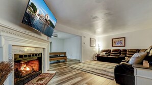 Una sala de estar con chimenea, televisor montado en la pared, sofá y alfombra.