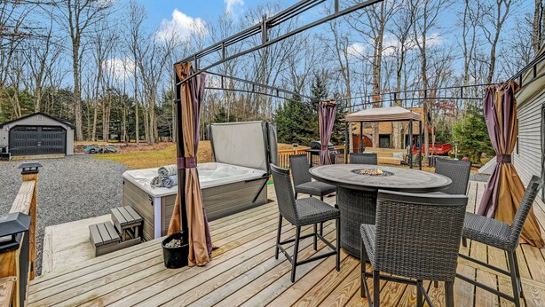 Una terraza con mobiliario exterior, un jacuzzi y una zona de estar cubierta.