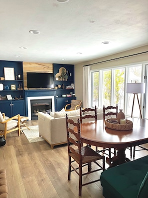 Uma sala de estar moderna com lareira, mesa de jantar e área de estar.