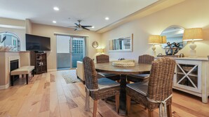 A dining area with wicker chairs, a wooden table, and a television. - Just Beachy: a charming townhome steps from Beach & Boardwalk in Pacific Beach! (San Diego)