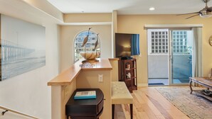 A modern living room with a wooden bench, a small table, and a television. - Just Beachy: a charming townhome steps from Beach & Boardwalk in Pacific Beach! (San Diego)