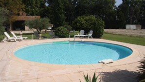 A circular pool with lounge chairs and a small shed in a landscaped backyard. - Holiday Home 'Le Mas Des Fleurs' with Private Pool, Private Terrace and Wi-Fi (Avignon)
