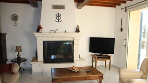 A living room with a fireplace, a television, a coffee table, and a sofa. - Holiday Home 'Le Mas Des Fleurs' with Private Pool, Private Terrace and Wi-Fi (Avignon)