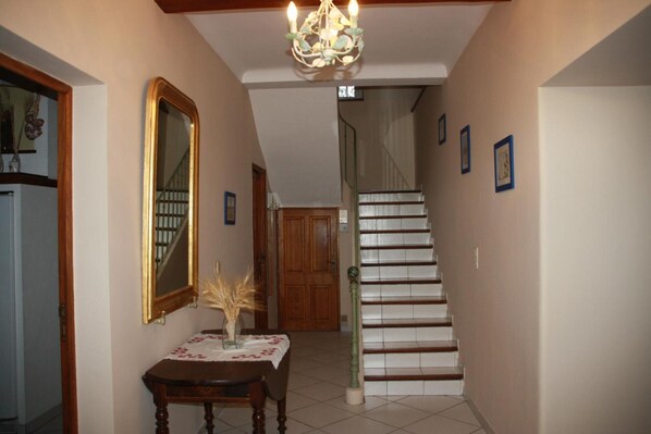 A staircase leading to a second floor, a wooden table with a vase, and a mirror on the wall.