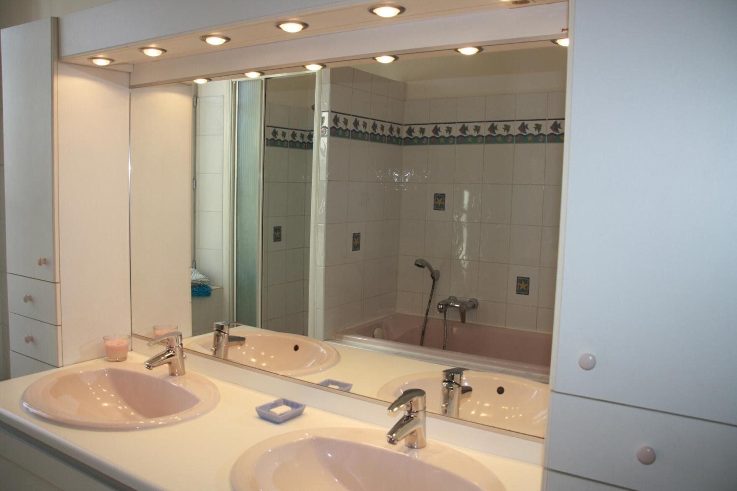 A bathroom with two sinks, a large mirror, and a shower.