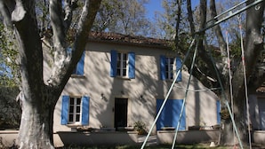A two-story building with blue shutters, a tiled roof, and a garden with potted plants. - Holiday Home 'Le Mas Des Fleurs' with Private Pool, Private Terrace and Wi-Fi (Avignon)