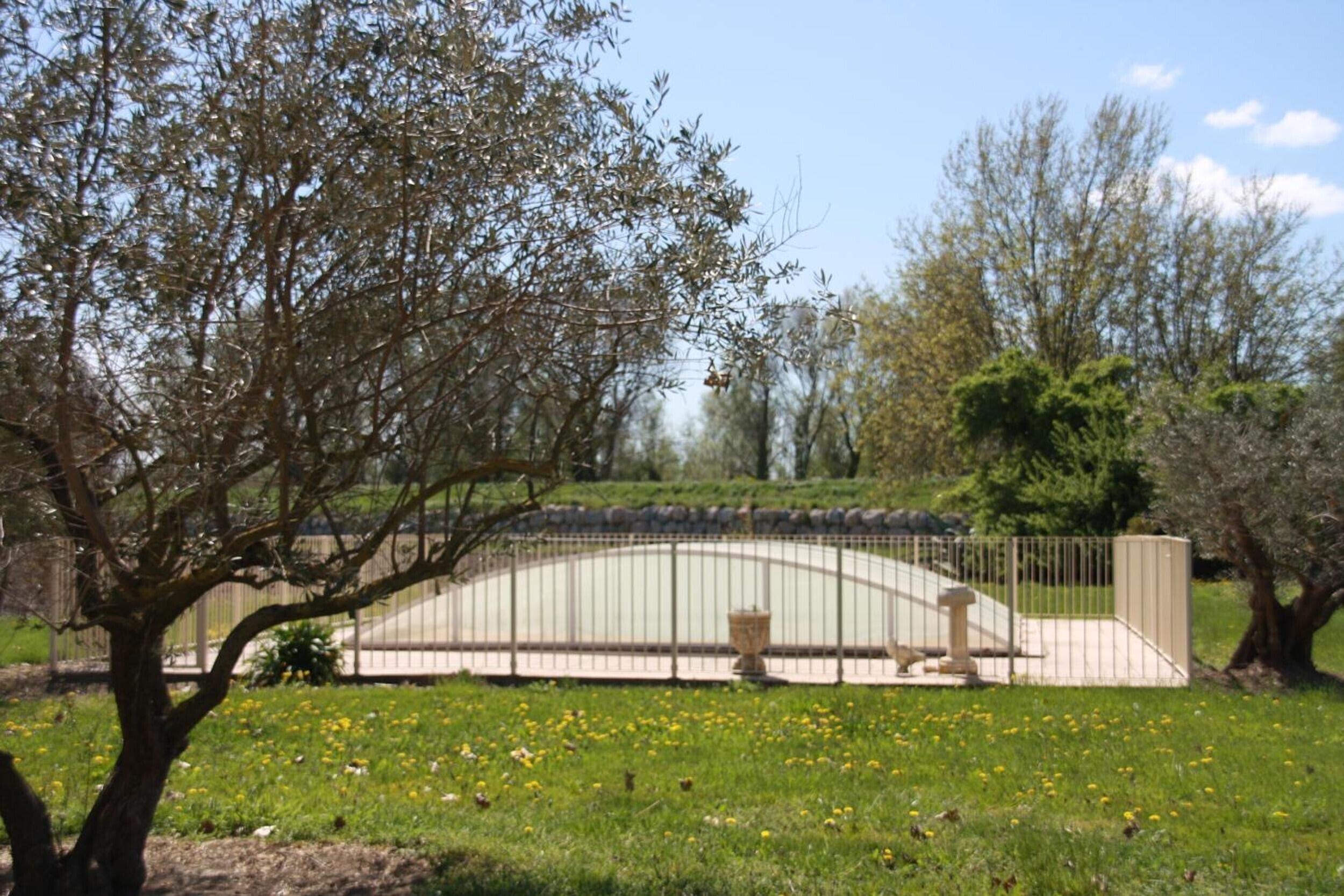 Un parco con un ponte in pietra, un muro di pietra e un'area recintata con una statua.